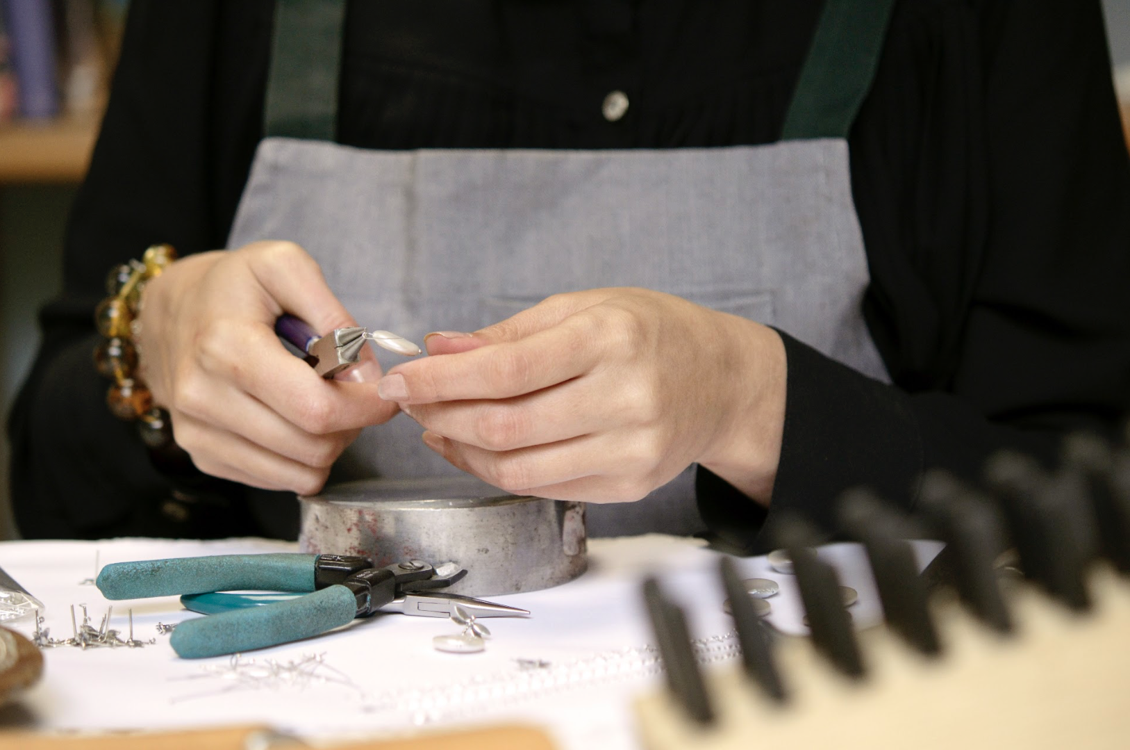 Mains assemblant un bijou à l’atelier